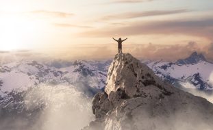 Adult,Adventurous,Woman,Standing,On,Top,Of,A,Snow,Peak.